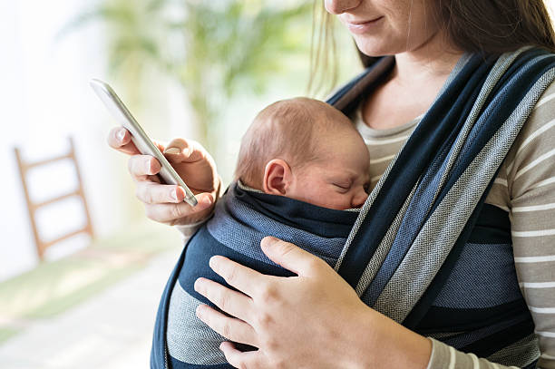 istock Unrecognizable mother with her son in sling and smartphone 615413842