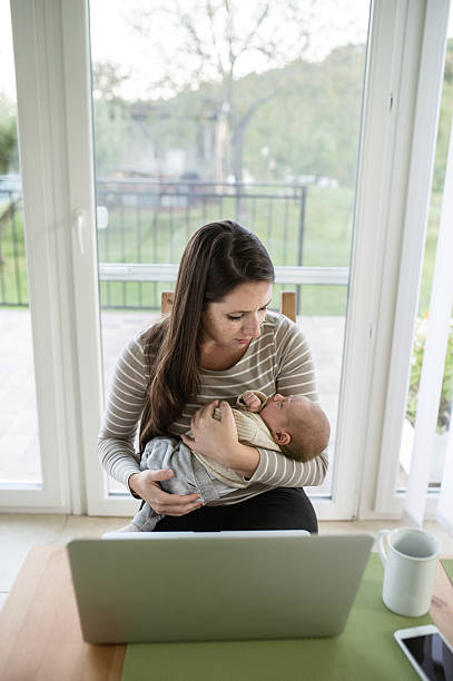 istock Young mother holding baby son, notebook on table 615414258