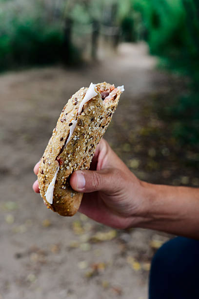 istock young man eating a sandwich outdoors 615414414