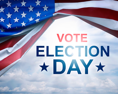 Vote Election Day written on under the USA flag with cloud sky background