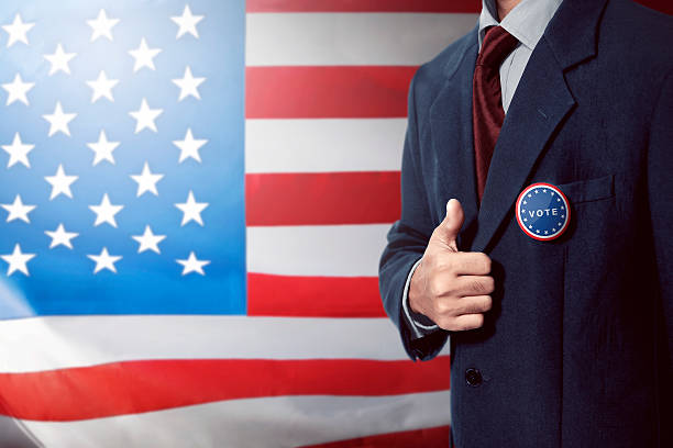 istock Man with black business suit with vote pinned button give 615417802