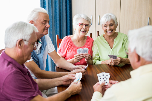 Seniors playing cards together in a retirement home