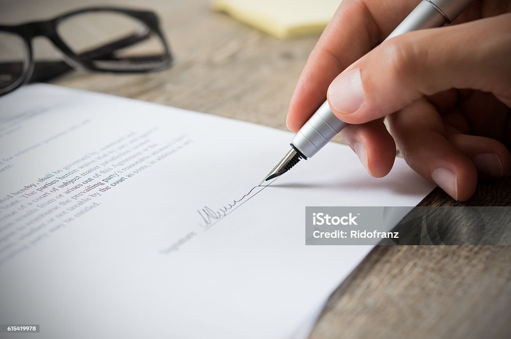 Man signing contract Close up of hand of businessman signing a form. Business man signing contract for future deal. Business man signing legal document. Male hand signing employee contract with a bond. Signing Stock Photo