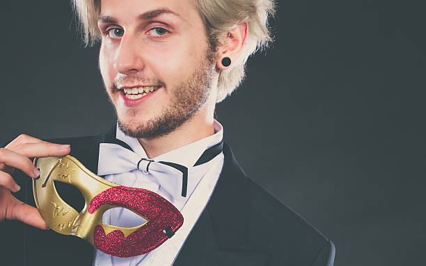 istock Young man in carnival mask on dark 615421960