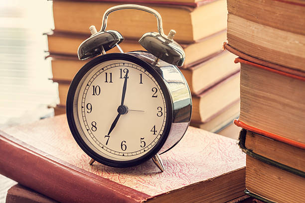 istock Pile of books with o'clock on desk 615425346