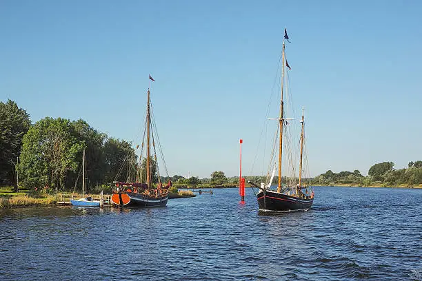 Two old wooden sailboats on river Trave in summer with blue sky