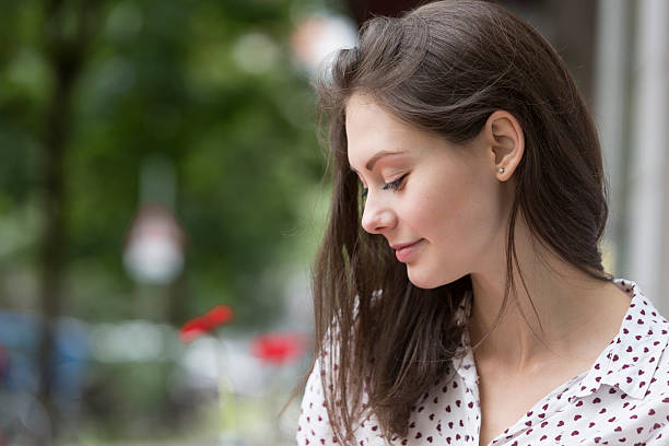 Profile of a beautiful woman absorbed in her thoughts and looking down. Copy space.