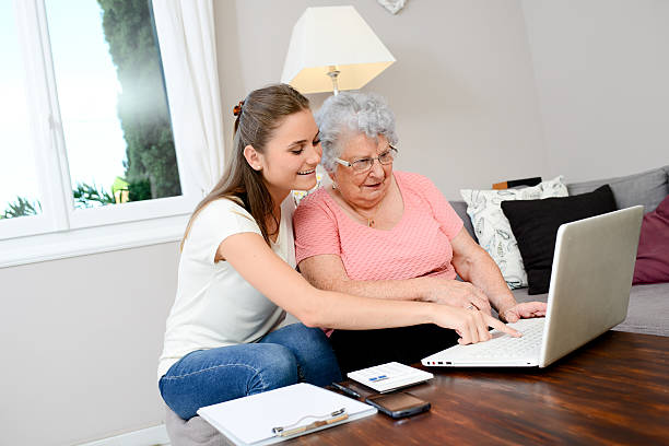 istock cheerful young woman giving computer lesson course to elderly woman 615427710