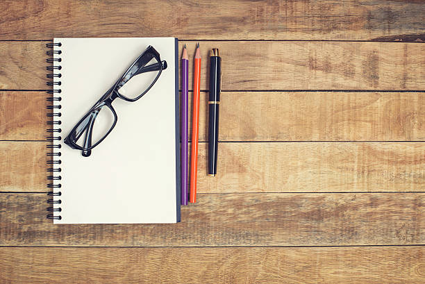 gafas y cuaderno con bolígrafo colocados sobre una mesa de madera - spiral notebook ring binder old paper fotografías e imágenes de stock