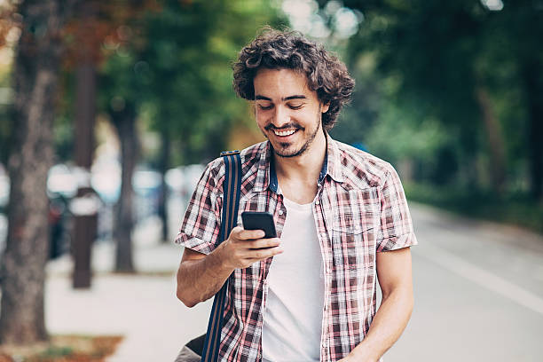 istock Cheerful man texting on the street 615430312