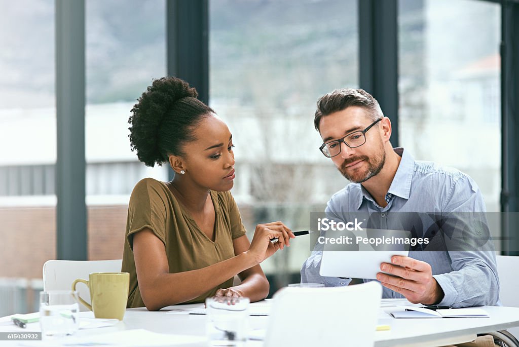 Perhaps we could make some improvements to this... Cropped shot of two colleagues working together on a digital tablet in an office Discussion Stock Photo