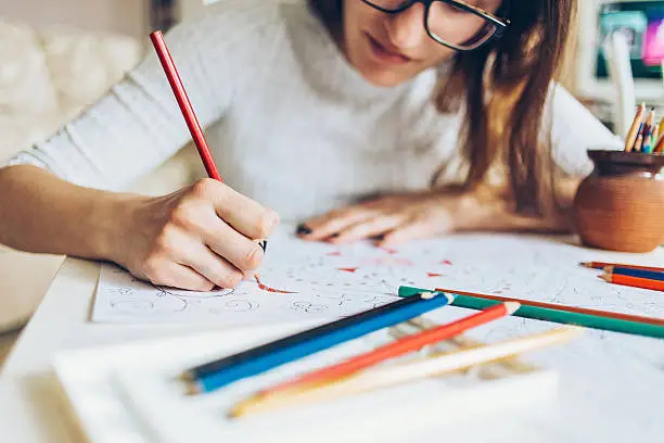 Woman coloring doodle with color pencils for relaxation.