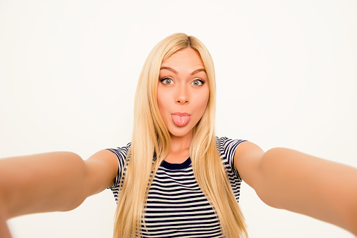 Funny woman making comic selfie and showing tongue