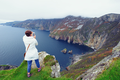 Woman taking pictures of Slieve League cliffs