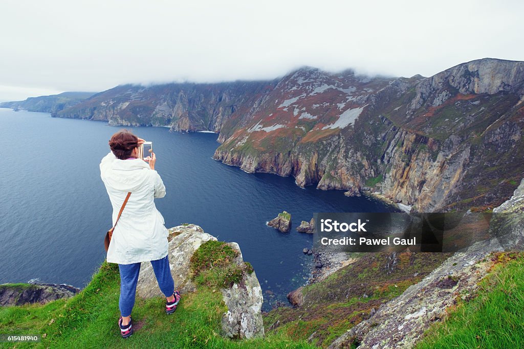 Woman taking pictures of Slieve League cliffs Adult Stock Photo