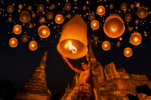 Thai woman with floating lamp in Ayuthaya historical park, with Wat Phra Sri Sanphet temple background, Thailand