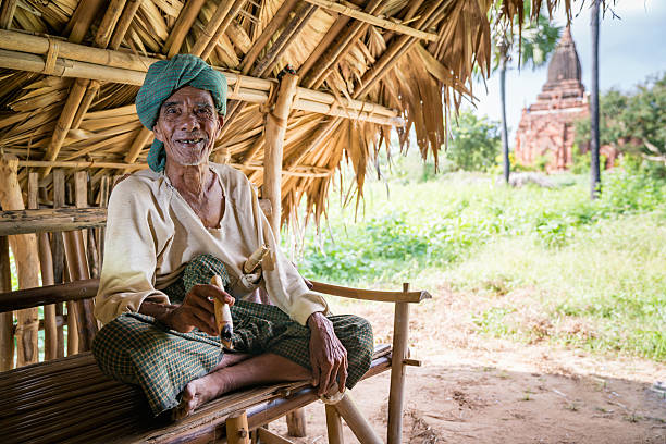 бирманский старик хат курение сигара баган мьянма - burmese culture myanmar old outdoors стоковые фото и изображения