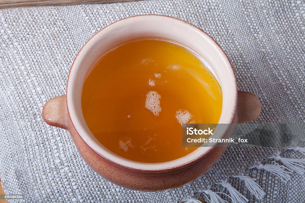 Clay pot with ghee and spoon on linen napkin Clay pot with ghee and spoon on linen napkin. Rustic still life. Wooden background. Bakery Stock Photo