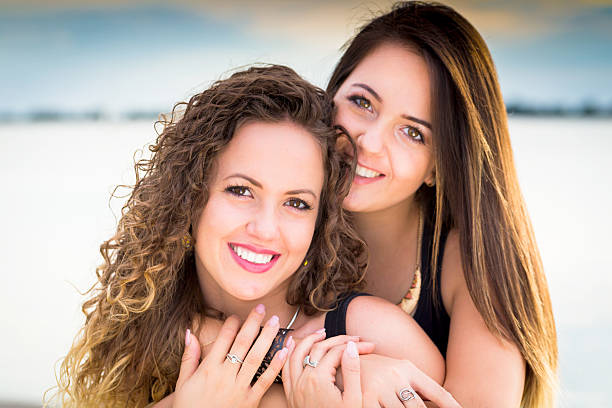 istock two beautiful young girlfriends embracing on lake 615497022