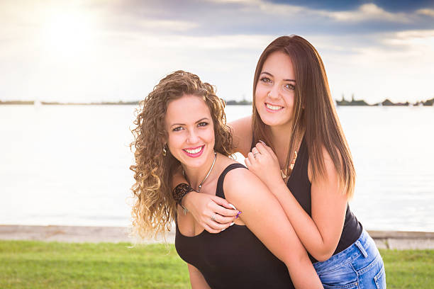istock two beautiful young girlfriends embracing on lake 615497306