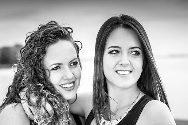 istock two beautiful young girlfriends embracing on lake 615497618