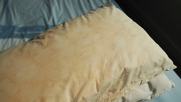 Dirty pillow from saliva stain on the bed. Dirty pillow from saliva stain on the bed. Dirty pillow with pale yellow and brown color. pillow stock pictures, royalty-free photos & images