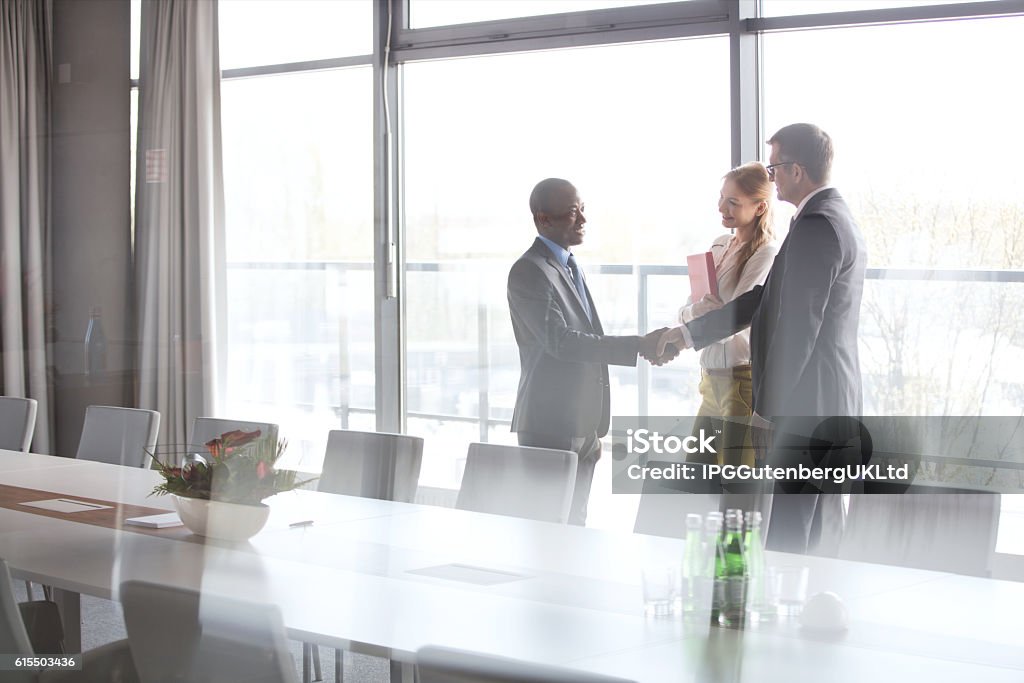 Corporate Business Businessmen shaking hands by female colleague in conference room at office Handshake Stock Photo