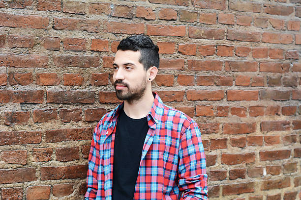 istock Portrait of young man against brick wall. 615505824