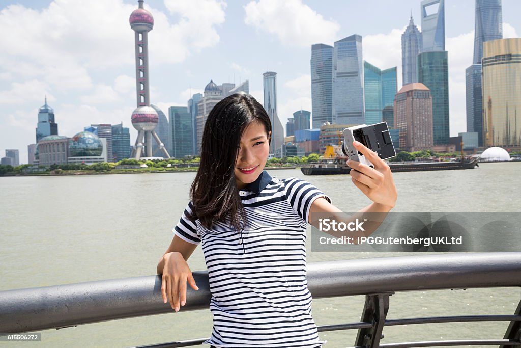 Smiling woman taking selfie Smiling woman taking selfie while standing by railing against Pudong skyline 20-24 Years Stock Photo
