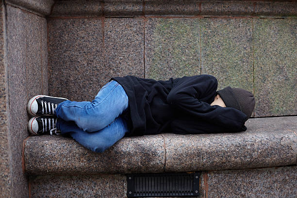 istock young homeless boy sleeping on the street 615506524