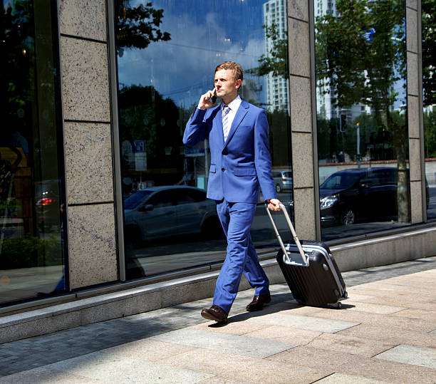 istock Man walking with suitcase and talking on the phone 615507016