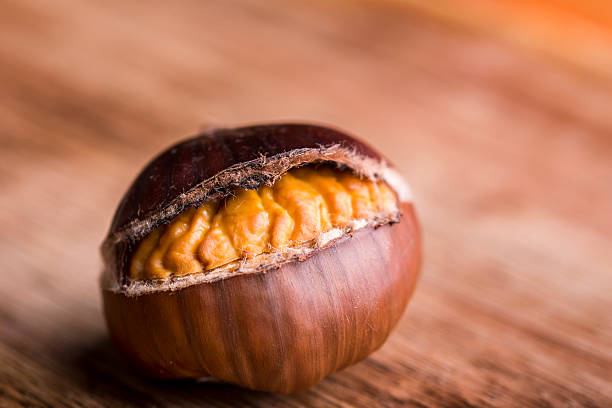 roasted chestnut macro isolated roasted chestnut on wooden table chestnut isolated single object autumn stock pictures, royalty-free photos & images