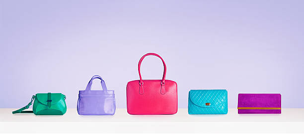 Colorful bags and purses isolated on purple background with copyspace. stock photo