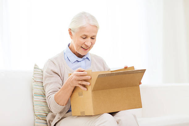 istock happy senior woman with parcel box at home 615512530