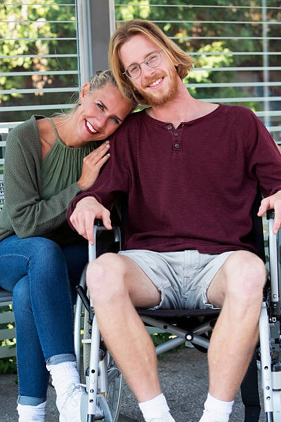 istock woman hugging young man in wheelchair 615512912