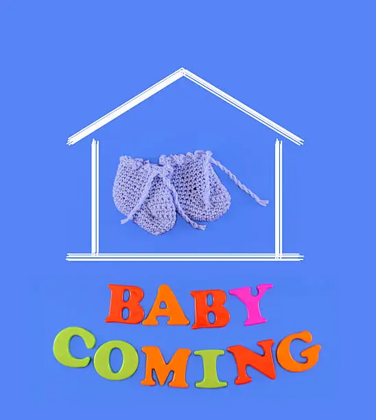 Baby shoes on light blue background, with text Baby coming. Baby shower concept in flat lay
