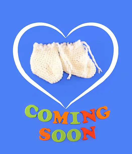 Baby shoes on light blue background, with text Coming Soon. Baby shower concept in flat lay