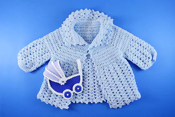 Hand-knit Organic Wool Baby Clothes. Baby shower concept in flat lay