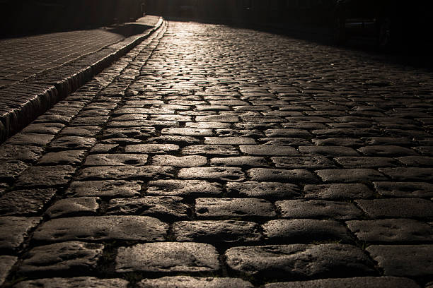 istock Black cobbled stone road background with reflection of light . 615517926