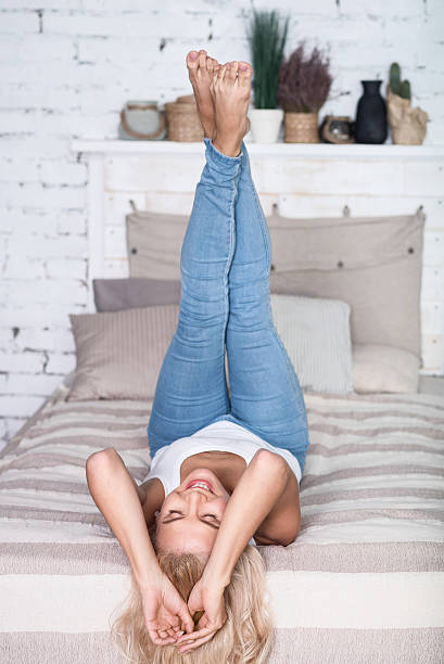 istock Blond woman with legs up on bed 615520812