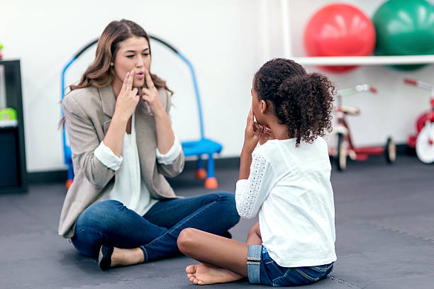 erwachsene therapeutin führt junges mädchen in der sprachtherapie - child speech therapy adult stock-fotos und bilder