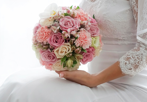 Close-up of bride sitting and holding a wedding bouquet.