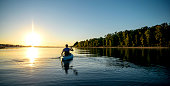 Adult male paddling a kayak on a river at sunset