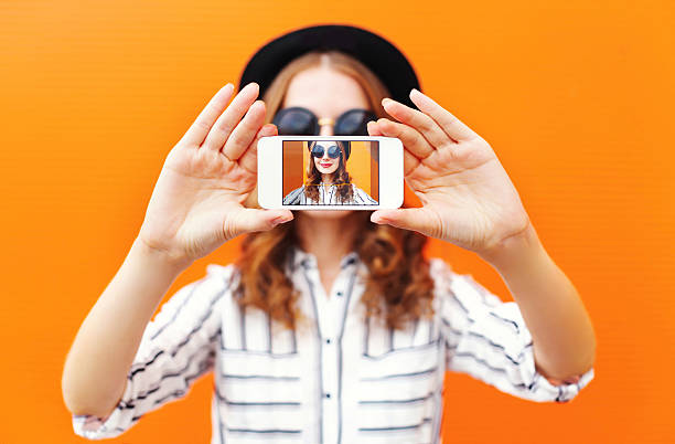 Fashion cool girl taking picture self portrait on smartphone stock photo
