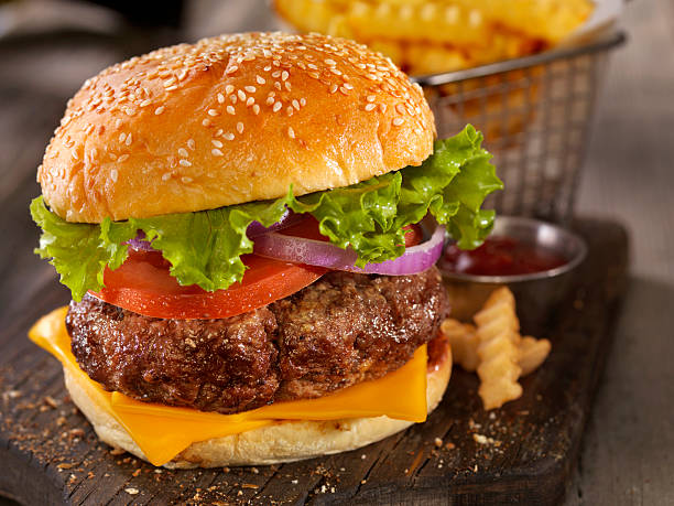 cheeseburger deluxe con un cesto di patatine fritte - burger french fries cheeseburger hamburger foto e immagini stock