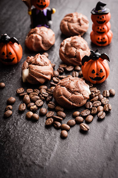 istock Eclairs and coffee beans with halloween decoration on black background 615603514