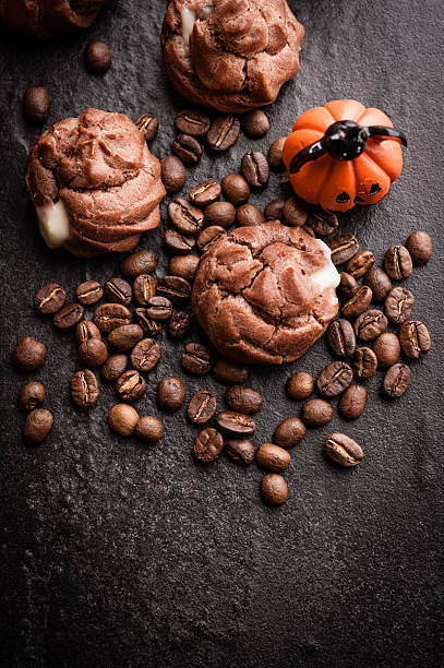 istock Eclairs and coffee beans with halloween decoration on black background 615603544