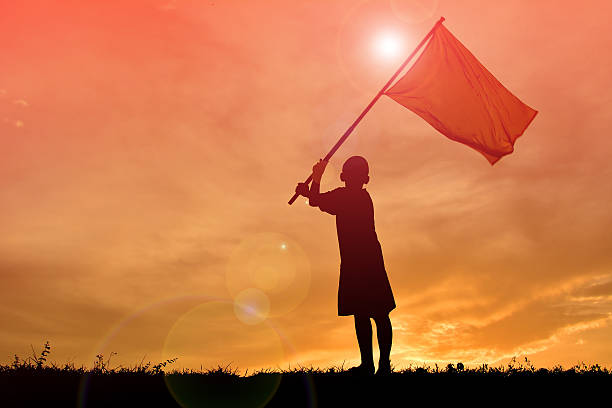 istock Silhouette boy holding flag at sunset. 615606074