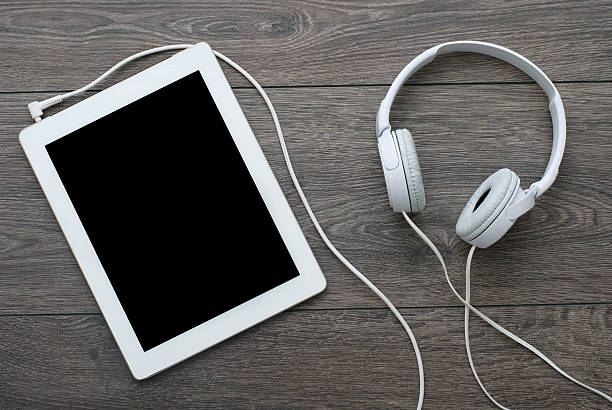 tablet with earphones on wooden surface stock photo