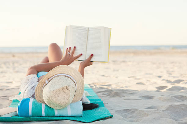 istock Woman enjoys reading a book on the beach 615610566